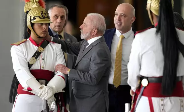 Brazil's President Luiz Inacio Lula da Silva, center, adjusts the helmet of a presidential guard after a meeting with Indonesia's President Prabowo Subianto at Planalto presidential palace in Brasilia, Brazil, Wednesday, July 9, 2025. (AP Photo/Eraldo Peres)