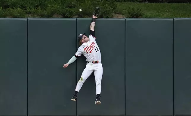 Minnesota Twins center fielder Harrison Bader (12) tries to catch a two-run home run by Chicago Cubs' Pete Crow-Armstrong during the third inning of a baseball game, Thursday, July 10, 2025, in Minneapolis. (AP Photo/Abbie Parr)