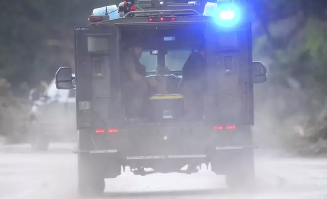 Officials ride an armored vehicle near Camp Mystic along the Guadalupe River after a flash flood swept through the area Sunday, July 6, 2025, in Hunt, Texas. (AP Photo/Julio Cortez)