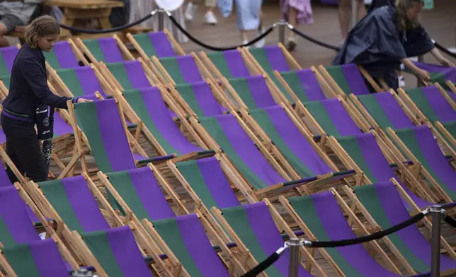 Workers remove water from deckchairs as the start of play is delayed due to rain during the Wimbledon Tennis Championships in London, Wednesday, July 2, 2025.(AP Photo/Kin Cheung)