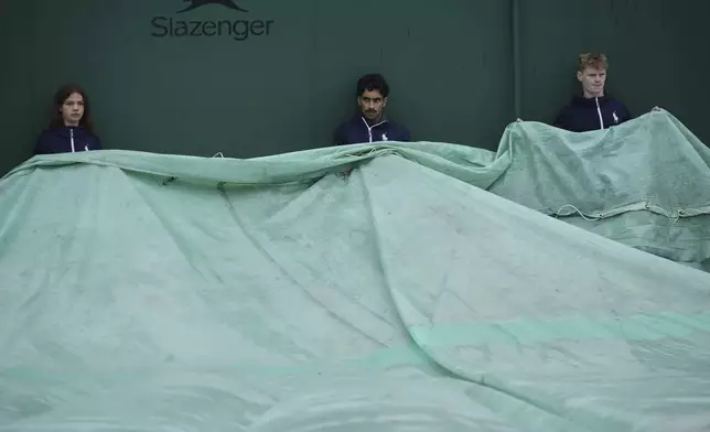 Ground staff prepare to uncover a court after a rainy start on day three at the Wimbledon Tennis Championships in London, Wednesday, July 2, 2025. (AP Photo/Alastair Grant)