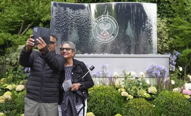 Spectators take a selfie as they arrive in the rain for day three at the Wimbledon Tennis Championships in London, Wednesday, July 2, 2025. (AP Photo/Joanna Chan)
