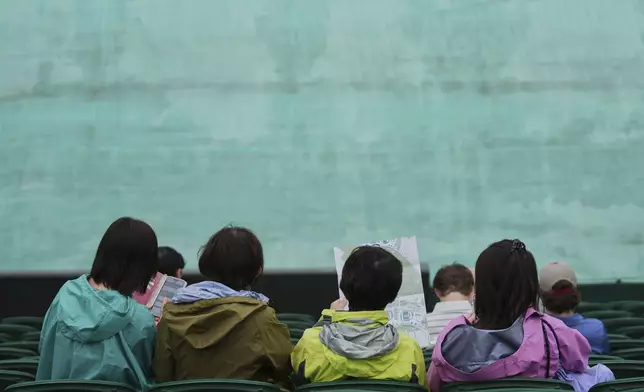 Spectators wait for the rain to pass on day three at the Wimbledon Tennis Championships in London, Wednesday, July 2, 2025. (AP Photo/Joanna Chan)