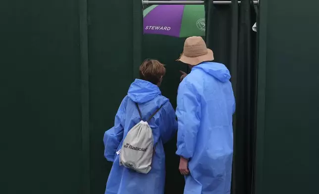 Spectators in rain clothing check the entrance to court 3 as the start of play is delayed due to rain during the Wimbledon Tennis Championships in London, Wednesday, July 2, 2025.(AP Photo/Kirsty Wigglesworth)