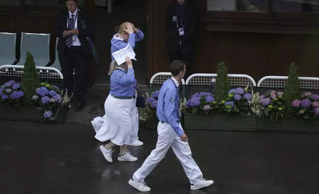 Officials try to remain dry as rain falls on day three at the Wimbledon Tennis Championships in London, Wednesday, July 2, 2025. (AP Photo/Alastair Grant)