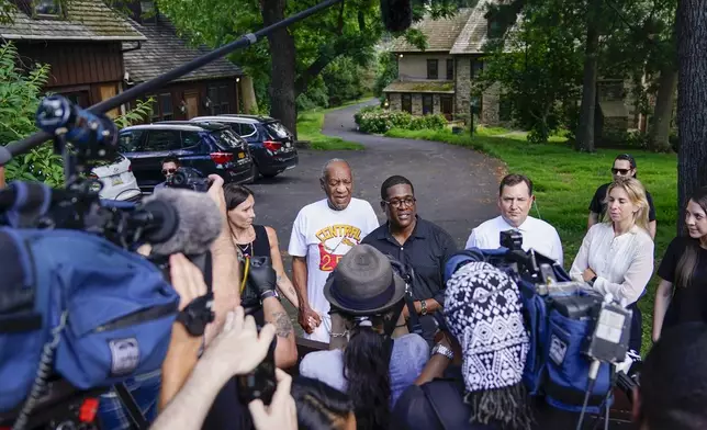 FILE - Bill Cosby, center, and spokesperson Andrew Wyatt, right, approach members of the media gathered outside the home of the entertainer in Elkins Park, Pa., June 30,2021. (AP Photo/Matt Slocum, File)