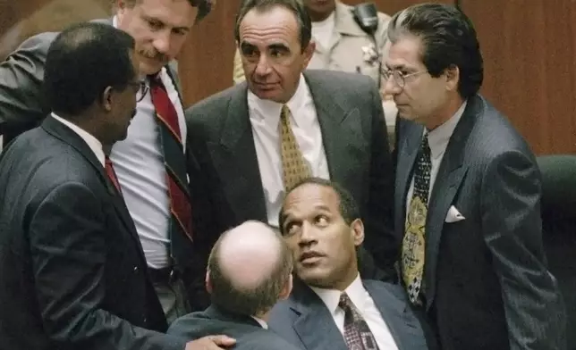 FILE- Defendant O.J. Simpson is surrounded by his defense attorneys, from left, Johnnie L. Cochran Jr., Peter Neufeld, Robert Shapiro, Robert Kardashian, and Robert Blasier, seated at left, at the close of defense arguments in his murder trial, Sept. 28, 1995, in Los Angeles. (Sam Mircovich/Pool Photo via AP, File)