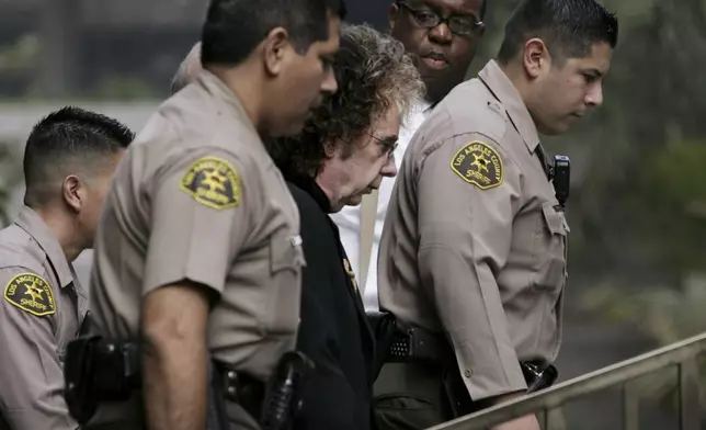 FILE - Music producer Phil Spector, center, is escorted to his car by Los Angeles County Sheriff deputies, Sept. 27, 2004, in Los Angeles after an indictment charging him with murder in the 2003 death of a B-movie actress at his Alhambra, Calif., mansion, was unsealed. (AP Photo/Kevork Djansezian, File)