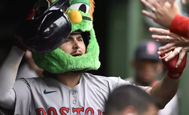Boston Red Sox's Wilyer Abreu celebrates with teammates in the dugout while wearing the green monster mask after hitting a solo home run during the eighth inning of a baseball game against the Chicago Cubs, Sunday, July 20, 2025, in Chicago. (AP Photo/Paul Beaty)