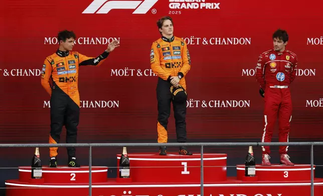 First place, McLaren driver Oscar Piastri of Australia, center, celebrates on the podium with second place McLaren driver Lando Norris of Britain, left, and third place Ferrari driver Charles Leclerc of Monaco during the Formula One Grand Prix at the Spa-Francorchamps racetrack in Spa, Belgium, Sunday, July 27, 2025. (AP Photo/Geert Vanden Wijngaert)