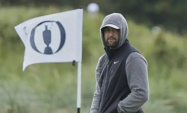 Scottie Scheffler of the United States keeps warm after putting on the 9th green during a practice round for the British Open golf championship at the Royal Portrush Golf Club, Northern Ireland, Tuesday, July 15, 2025. (AP Photo/Jon Super)