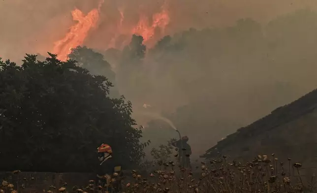 Firefighters try to extinguish a major forest fire in the village of Karteri, near Corinth, west of Athens, Greece, on Tuesday, July 22, 2025. (AP Photo/Vasilis Psomas)