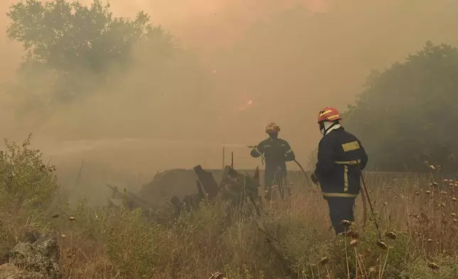 Firefighters try to extinguish a major forest fire in the village of Karteri, near Corinth, west of Athens, Greece, on Tuesday, July 22, 2025. (AP Photo/Vasilis Psomas)