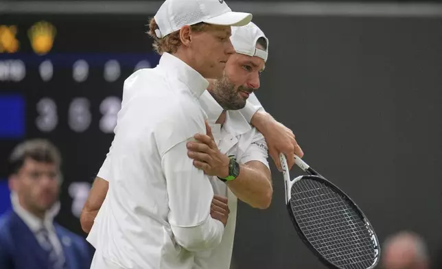 Italy's Jannik Sinner, left, assists Bulgaria's Grigor Dimitrov after he went down with an injury which forced him to retire from a fourth round men's singles match at the Wimbledon Tennis Championships in London, Monday, July 7, 2025. (AP Photo/Kin Cheung)