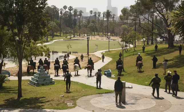 Federal agents ride on horseback at MacArthur Park, Monday, July 7, 2025, in Los Angeles. Their uniforms read "Police U.S. Border Patrol," and "HSI," which stands for Homeland Security Investigations. (AP Photo/Damian Dovarganes)