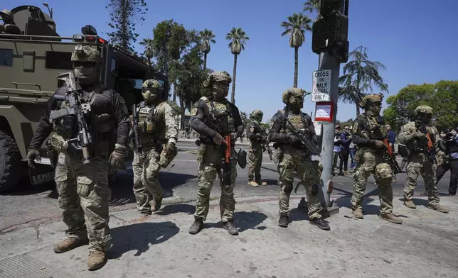 Federal agents stage at MacArthur Park Monday, July 7, 2025, in Los Angeles. (AP Photo/Damian Dovarganes)
