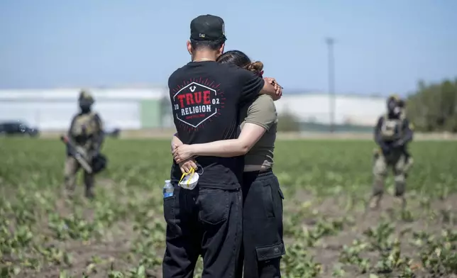 Arturo Rangel hugs Judith Ramos whose father works at the greenhouse in the background as federal immigration agents block access during a raid in the agriculture area of Camarillo, Calif., Thursday, July 10, 2025. (AP Photo/Michael Owen Baker)