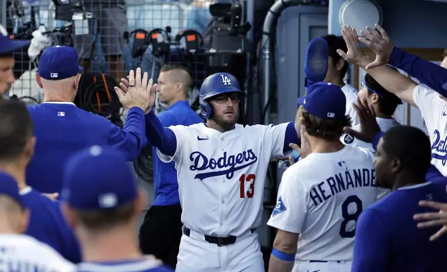 Los Angeles Dodgers' Max Muncy is congratulated after scoring a run against the Chicago White Sox during the first inning of a baseball game Tuesday, July 1, 2025, in Los Angeles. (AP Photo/Kevork Djansezian)