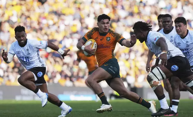 Australia's Noah Lolesio, center, makes a break against Fiji during their rugby union international match in Newcastle, Australia, Sunday, July 6, 2025. (AP Photo/Mark Baker)