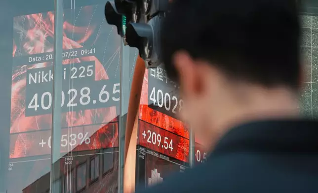 A person stands in front of an electronic stock board showing Japan's Nikkei index at a securities firm Tuesday, July 22, 2025, in Tokyo. (AP Photo/Eugene Hoshiko)