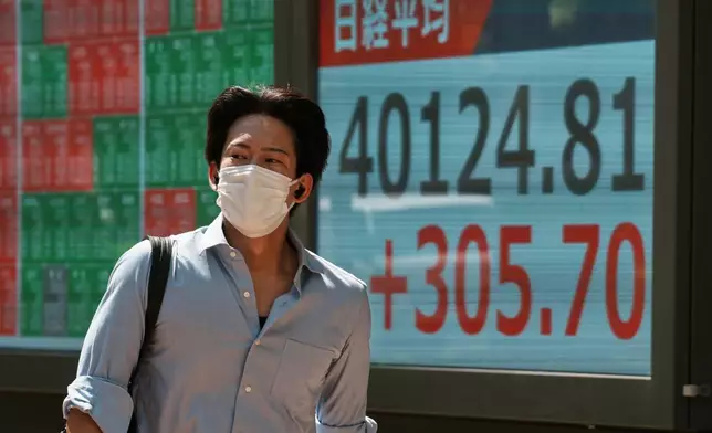 A person walks in front of an electronic stock board showing Japan's Nikkei index at a securities firm Tuesday, July 22, 2025, in Tokyo. (AP Photo/Eugene Hoshiko)