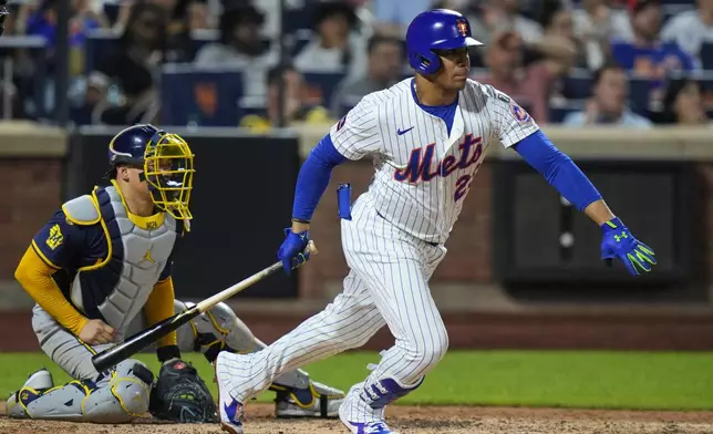 New York Mets' Juan Soto follows through on a RBI single as Milwaukee Brewers catcher William Contreras watches during the sixth inningof a baseball game Thursday, July 3, 2025, in New York. (AP Photo/Frank Franklin II)