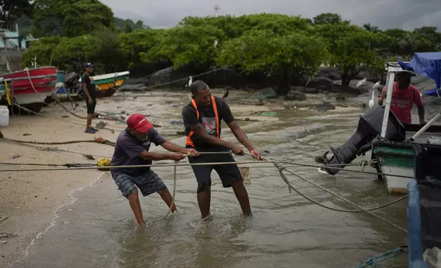 Fishermen pull their boats on to the shore in Veracruz, Panama, Wednesday, July 30, 2025, as a precaution due to a tsunami warning after an earthquake struck off the coast of Russia. (AP Photo/Matias Delacroix)
