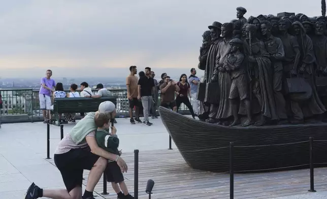 People look at a sculpture that pays tribute to migrants and refugees at the national shrine of Saint Joseph's Oratory of Mount Royal in Montreal, Saturday, June 28, 2025. (AP Photo/Luis Andres Henao)