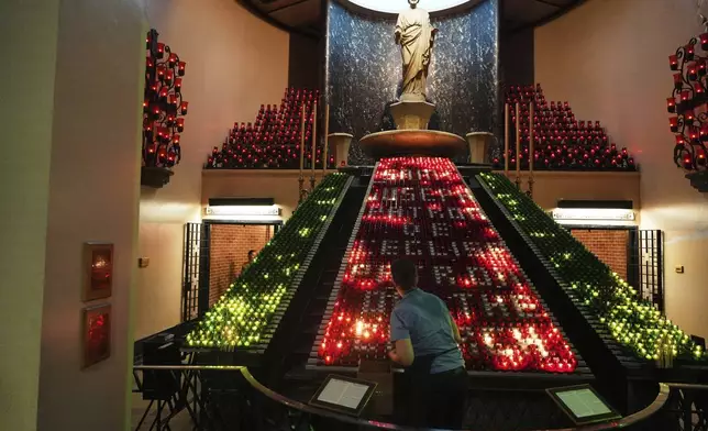 A worker arranges candles inside the Votive Chapel at the national shrine of Saint Joseph's Oratory of Mount Royal, in Montreal, Saturday, June 28, 2025. (AP Photo/Luis Andres Henao)