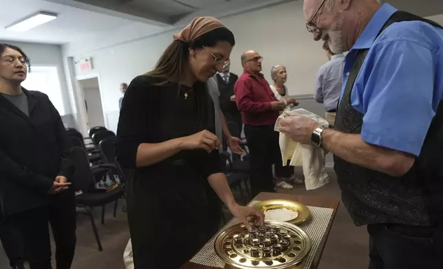 Megane Ares-Dube, center, prepares to receive communion during service at the Reformed Baptist Church in Saint Jerome, Quebec, Sunday, June 29, 2025. (AP Photo/Luis Andres Henao)