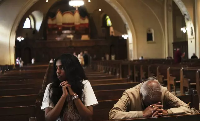 Thurvi Valli and her grandfather, Sitham Valli pray inside Crypt Church at the national shrine of Saint Joseph's Oratory of Mount Royal, in Montreal, Saturday, June 28, 2025. (AP Photo/Luis Andres Henao)