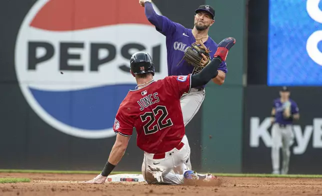 Colorado Rockies' Kyle Farmer, rear, forces Cleveland Guardians' Nolan Jones (22) out at second base and throws to first to complete a double play during the fourth inning of a baseball game, Tuesday, July 29, 2025, in Cleveland. (AP Photo/Phil Long)