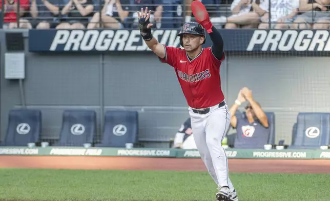 Cleveland Guardians' Steven Kwan signals to Daniel Schneemann not to slide after scoring on an RBI single by Gabriel Arias off Colorado Rockies starting pitcher Tanner Gordon during the first inning of a baseball game, Tuesday, July 29, 2025, in Cleveland. (AP Photo/Phil Long)