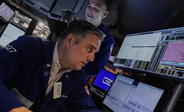 Traders James Bodner, foreground, and Christopher Lagana work on the floor of the New York Stock Exchange, Friday, July 18, 2025. (AP Photo/Richard Drew)