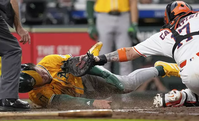 Athletics' Max Schuemann, left, is tagged out at home plate by Houston Astros catcher Victor Caratini (17) during the fourth inning of a baseball game Thursday, July 24, 2025, in Houston. (AP Photo/David J. Phillip)