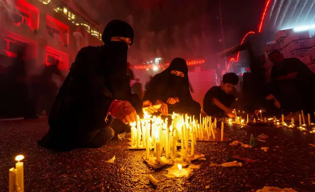 Shiite faithful pilgrims light candles outside the holy shrine of Imam Hussein during a Muharram procession marking Ashoura, to commemorate the martyrdom of Imam Hussein, grandson of the Prophet Muhammad, in Karbala, Iraq, Sunday, July 6, 2025. (AP Photo/Anmar Khalil)