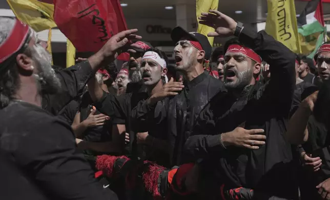 Hezbollah supporters raise their hands and beat their chests as they march during Ashoura, the Shiite Muslim commemoration marking the 7th-century death of Imam Hussein, the grandson of the Prophet Muhammad, at the Battle of Karbala, in the southern suburbs of Beirut, Lebanon, Sunday, July 6, 2025. (AP Photo/Hassan Ammar)