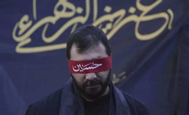 A Hezbollah supporter who lost his sight in a pager attack carried out by Israel on Sept. 17, 2024, covers his eyes with a red headband inscribed with the name "Hussein" during Ashoura, the Shiite Muslim commemoration marking the 7th-century death of Imam Hussein, the grandson of the Prophet Muhammad, in the southern suburbs of Beirut, Lebanon, Sunday, July 6, 2025. (AP Photo/Hassan Ammar)