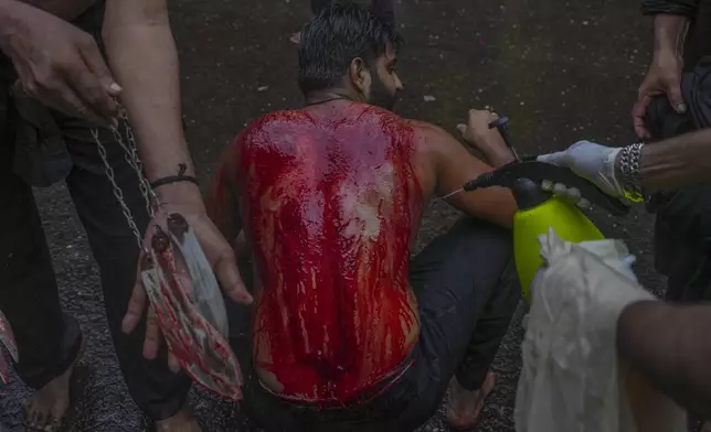 EDS NOTE: GRAPHIC CONTENT - A volunteer pours water on the body of a Shiite Muslim who bleeds after flagellating himself during an Ashoura procession marking the 7th-century death of Imam Hussein, the grandson of the Prophet Muhammad, in Mumbai, India, Sunday, July 6, 2025. (AP Photo/Rafiq Maqbool)