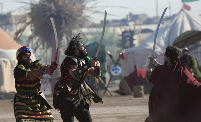 Shiite Muslims re-enact the seventh century battle of Karbala during activities marking the holy day of Ashoura, the annual Shiite Muslim commemoration marking the death of Imam Hussein, the grandson of the Prophet Muhammad, in the Shiite neighborhood of Sadr City, Baghdad, Iraq, Sunday, July 6, 2025. (AP Photo/Hadi Mizban)