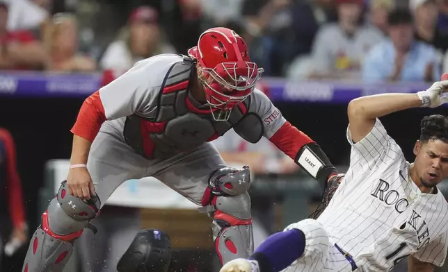 St. Louis Cardinals catcher Pedro Pagés, left, applies a late tag to Colorado Rockies' Ezequiel Tovar as he scores on a single hit by Brenton Doyle in the fifth inning of a baseball game Tuesday, July 22, 2025, in Denver. (AP Photo/David Zalubowski)