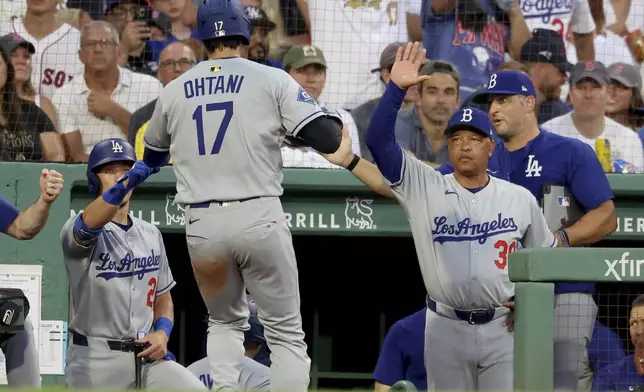 Los Angeles Dodgers designated hitter Shohei Ohtani (17) celebrates his run with a high five to manager Dave Roberts, right, during the third inning of a baseball game against the Boston Red Sox, Friday, July 25, 2025, in Boston. (AP Photo/Mark Stockwell)