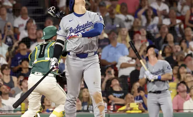 Los Angeles Dodgers designated hitter Shohei Ohtani, center, watches his high pop fly during the ninth inning of a baseball game against the Boston Red Sox, Friday, July 25, 2025, in Boston. (AP Photo/Mark Stockwell)