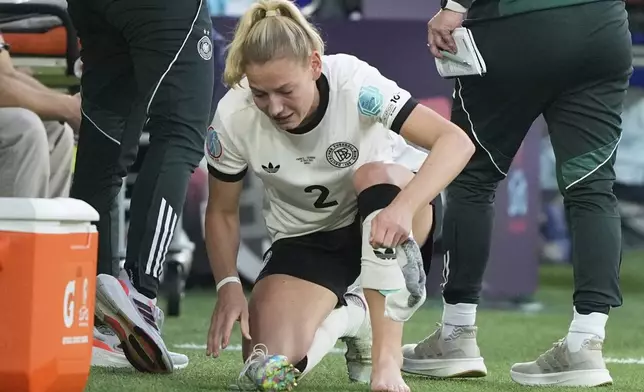 Germany's Sarai Linder take off her cleat after suffering an injury during the Women's Euro 2025 quarterfinals soccer match between France and Germany at St. Jakob-Park in Basel, Switzerland, Saturday, July 19, 2025. (AP Photo/Martin Meissner)