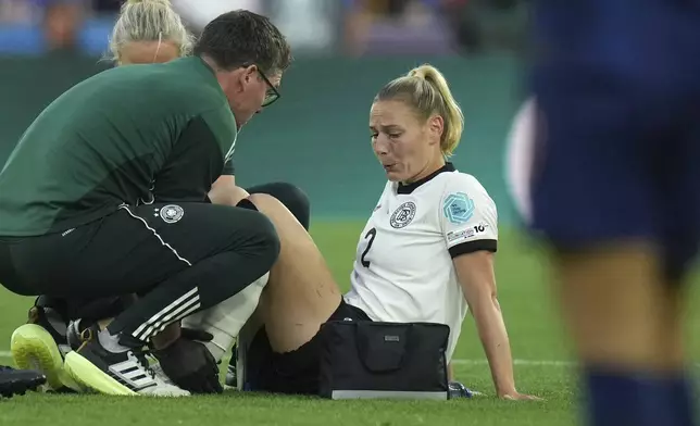 Germany's Sarai Linder is assisted after getting injured during the Women's Euro 2025 quarterfinals soccer match between France and Germany at St. Jakob-Park in Basel, Switzerland, Saturday, July 19, 2025. (AP Photo/Alessandra Tarantino)