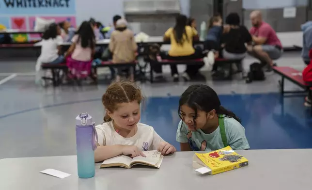 Girls read an Amelia Bedelia book during the East Providence Boys and Girls Club Summer Camp at Emma G. Whiteknact Elementary School on Thursday, July 10, 2025, in Providence R.I. (AP Photo/Sophie Park)