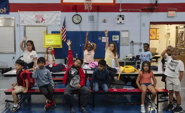 Children raise their hands while participating in activities during the East Providence Boys and Girls Club Summer Camp at Emma G. Whiteknact Elementary School on Thursday, July 10, 2025, in Providence R.I. (AP Photo/Sophie Park)