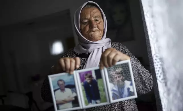 Saliha Osmanovic, 71, poses for a photo while holding pictures of her two sons and husband, victims of the Srebrenica genocide in the village of Dobrak near Srebrenica, Bosnia, on June 28, 2025. During the genocide a total of 38 members of her family were killed. (AP Photo/Armin Durgut)
