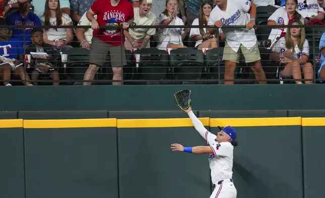 Texas Rangers outfielder Alejandro Osuna hops near the fence to try to catch a two-run home run by Baltimore Orioles' Gary Sánchez during the fourth inning of a baseball game Tuesday, July 1, 2025, in Arlington, Texas. (AP Photo/Julio Cortez)