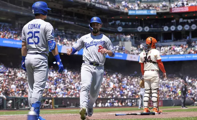 Los Angeles Dodgers' Michael Conforto, center, scores against the San Francisco Giants on Hyeseong Kim's single during the sixth inning of a baseball game Saturday, July 12, 2025, in San Francisco. (AP Photo/Godofredo A. Vásquez)